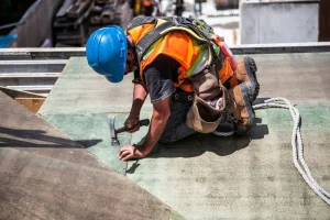 A Northampton Roofer in a hard hat is installing roofing materials on a house in Northampton.