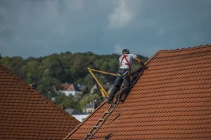 A man working on top of a roof completing work for a roofing company in Northampton